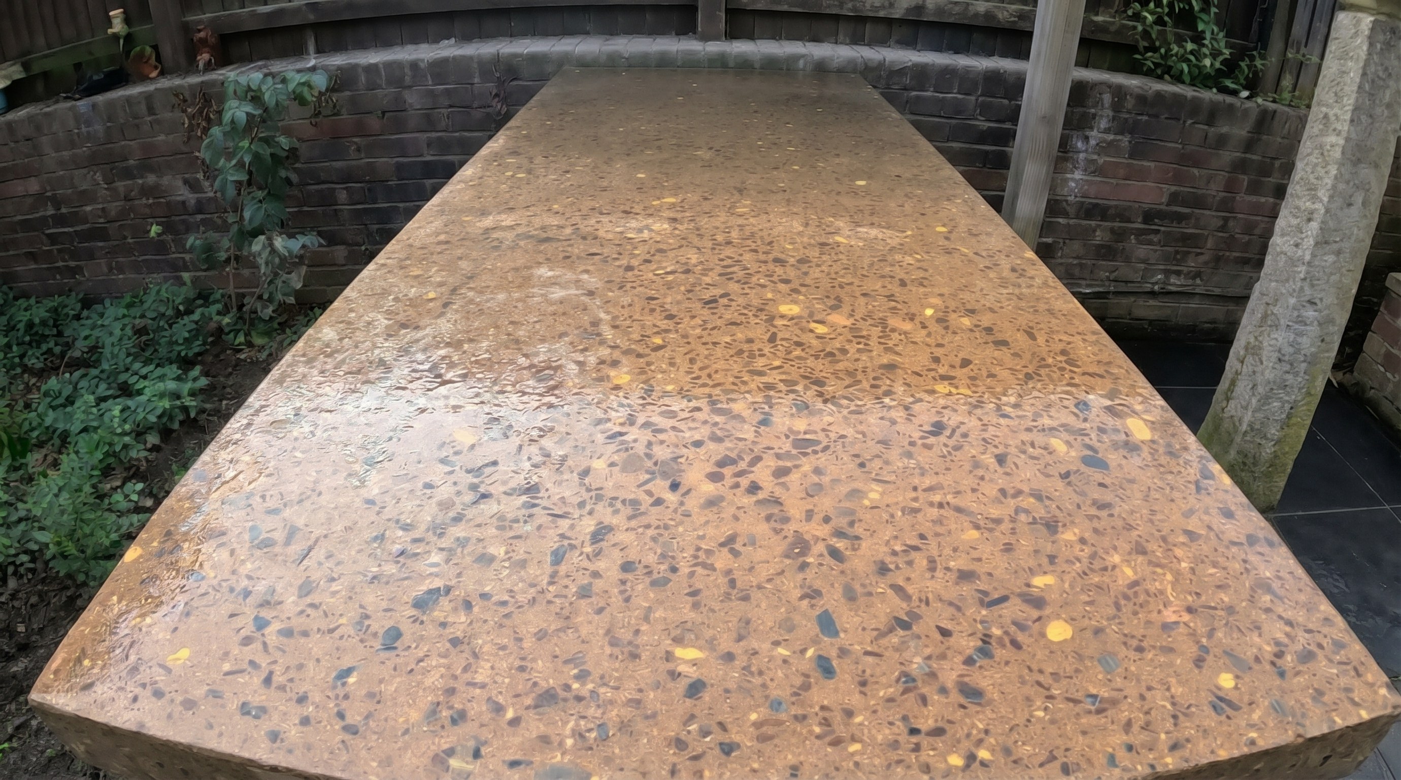 Polished concrete outdoor countertop with terrazzo finish on a clad block base in a garden patio